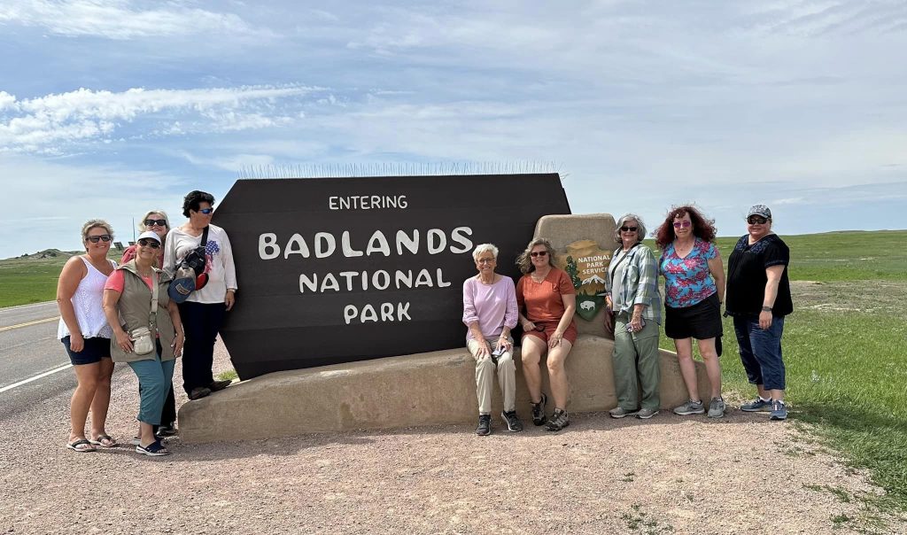 Group posing at Badlands National Park sign.