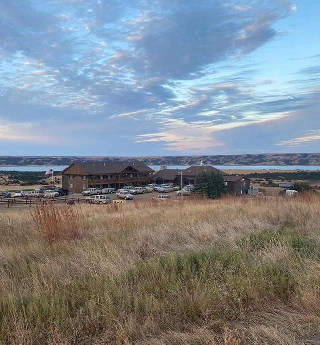 Lodge with scenic landscape and cloudy sky.