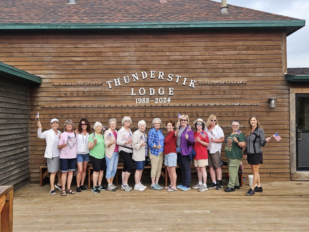 Group posing outside Thunderstik Lodge, smiling.