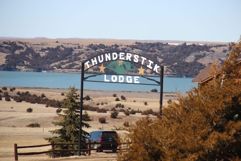 Thunderstik Lodge sign by scenic lake.
