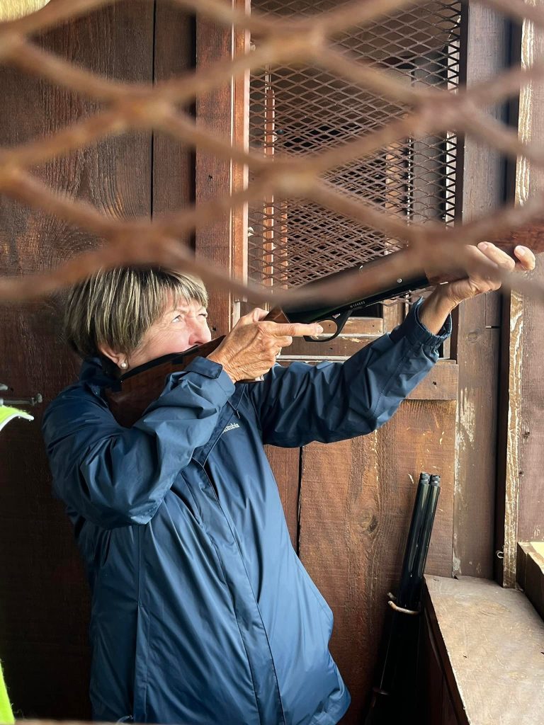 Person aiming rifle in a wooden booth.